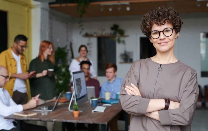 green business owner smiling with a group of people behind her